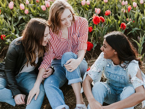 three women sitting in a field of flowers