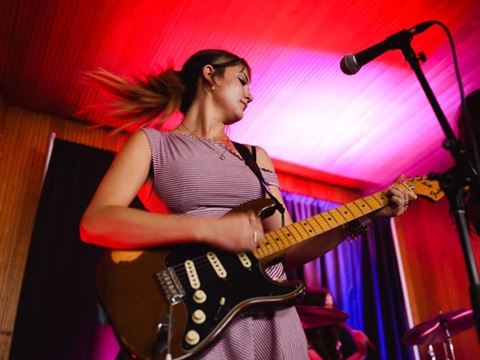 young person on stage playing guitar 
